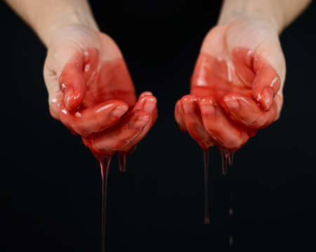 Womens hands in a viscous red liquid similar to blood.の写真素材