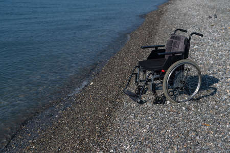 An empty wheelchair on a rocky seashore.の写真素材