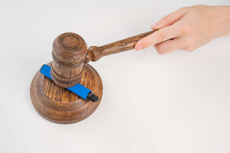 Judge hammering disposable vape with referees gavel on white table.の写真素材