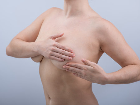 Caucasian woman self checks for breast cancer on white background.の写真素材