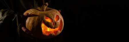 The witch is holding a pumpkin jack o lantern glowing in the dark. Halloween.の写真素材