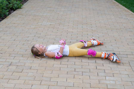 Little girl learns to roller skate and falls. View from above
