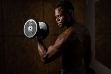 Attractive african american man doing biceps exercise with dumbbells.の写真素材