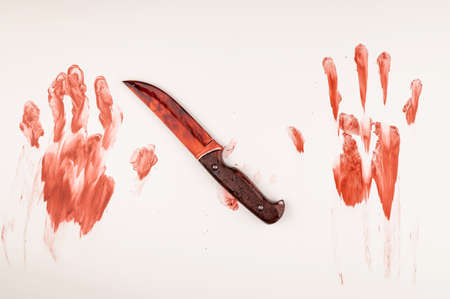 Bloody knife and hand prints in blood on a white table.の写真素材