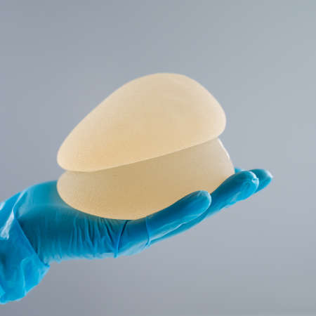 Doctor in a rubber glove holding a pile of breast implants.の写真素材