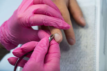 Manicurist cuts off cuticle to male client using nippers.の写真素材