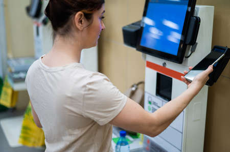 Woman paying with smartphone in store at self-checkout counter.の写真素材