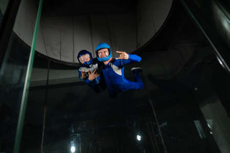 A man teaches a boy to fly in a wind tunnel. Lack of gravity.