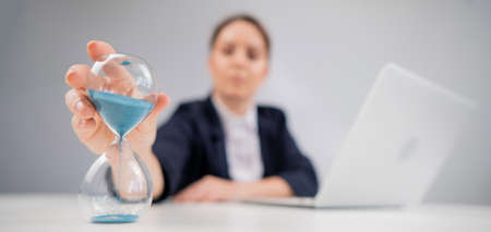 Business woman flipping an hourglass at her desk.の写真素材