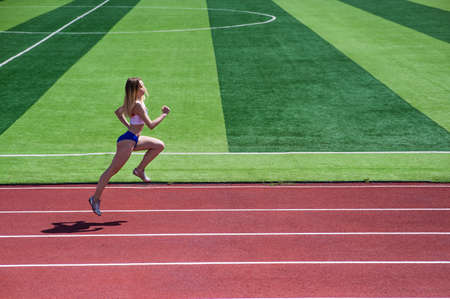 Young caucasian woman is engaged in jogging at the stadium outdoors.の写真素材