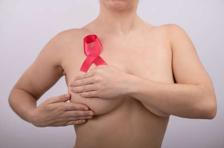 Caucasian woman self-checks for breast cancer. Pink satin ribbon.の写真素材