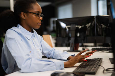 African young woman talking at her desk in the office.