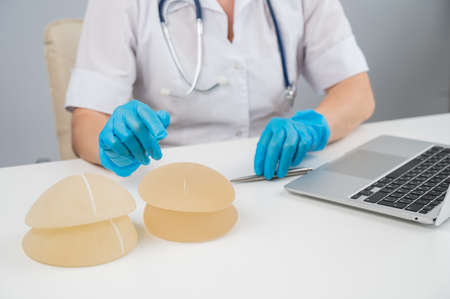 Doctor plastic surgeon explains the benefits of different breast implants.の写真素材