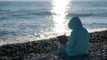 Caucasian woman working freelance on laptop on the beach.の写真素材