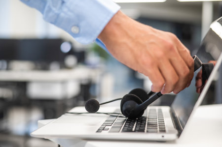 A man puts a headset on a laptop keyboard in the office.の写真素材
