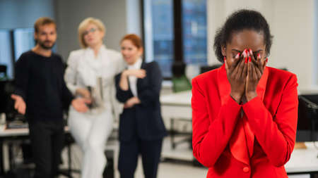 Young african woman crying because of the ridicule of colleagues. Racial discrimination in the...
