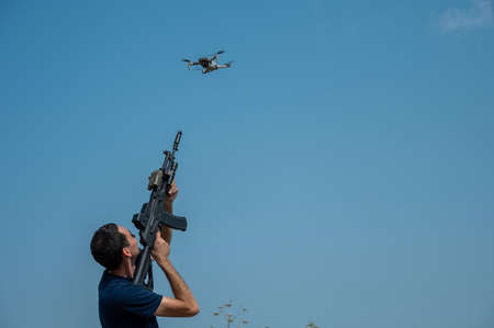 Caucasian man shoots a flying drone with a rifle.