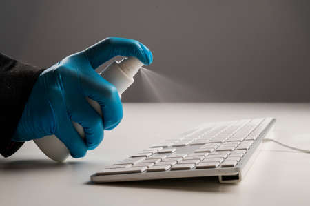 Close-up of a woman disinfects a white computer keyboard. Slow motion.