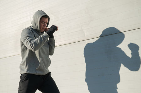 Caucasian man in hoodie is training boxing outdoors.の写真素材