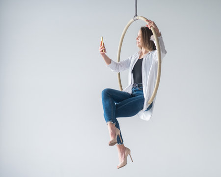Caucasian woman gymnast on an aerial hoop takes a selfie on a smartphone.の写真素材
