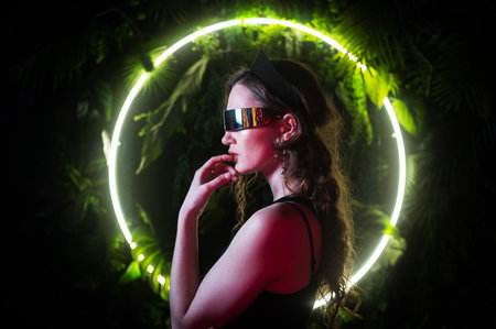 Caucasian woman in panoramic sunglasses against the background of an annular neon lamp in plants.の写真素材