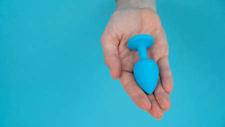 Woman holding a blue anal plug on a blue background.の写真素材