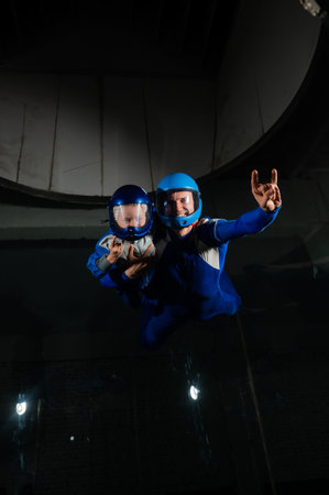A man teaches a boy to fly in a wind tunnel. Lack of gravity.