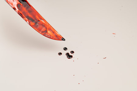 Close-up of a sharp knife covered in blood on a white background.の写真素材