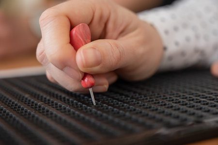 A woman uses a special stencil and stylus to write a letter in braille.の写真素材