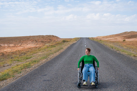 Woman in a wheelchair on a highway in the steppes.の写真素材