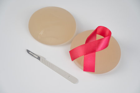 Breast silicone implants, pink tape and a disposable scalpel on a white background.