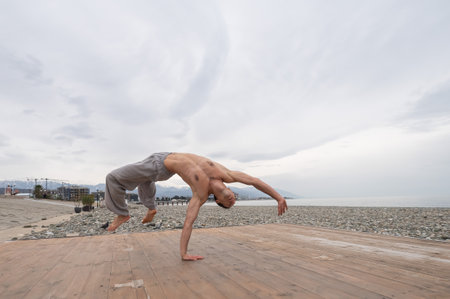 Shirtless caucasian man doing backflip on pebble beach.の写真素材