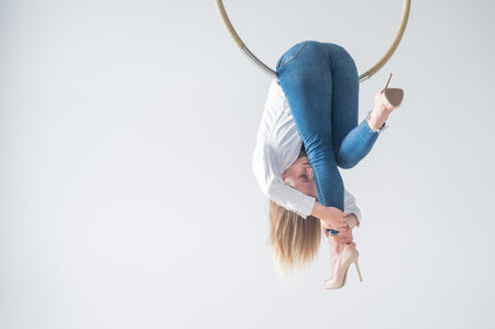 Caucasian woman in casual clothes on an aerial hoop.