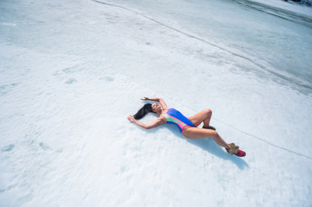 Caucasian woman in a swimsuit sunbathes on the snow in winter.