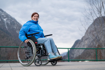 A woman in a wheelchair on a point view admires the high mountains. Thrust to life.の写真素材