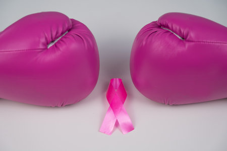 Pink boxing gloves and pink ribbon on a white background. The concept of the fight against breast cancer.の写真素材