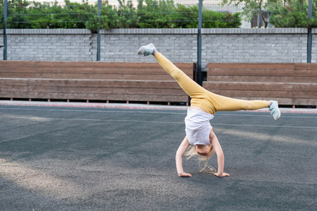 Caucasian girl makes a cartwheel on the sports field outdoors.
