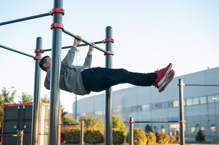 Young caucasian man doing parallel bars exercise outdoors.