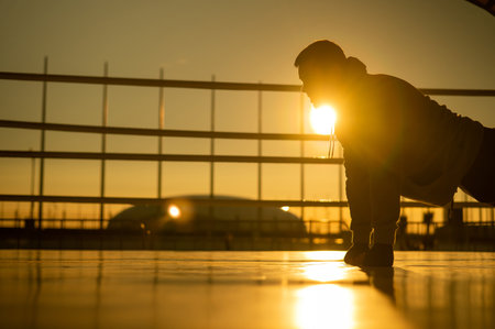 Young caucasian man doing push-ups in the boxing ring outdoors at sunset.の写真素材