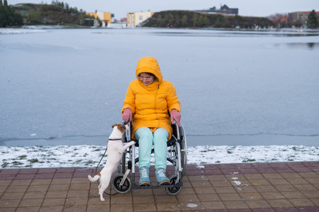 Caucasian woman in a wheelchair walks the dog in winter.の写真素材