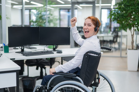 Caucasian woman with headset in a wheelchair. Happy female call center worker in the office.の写真素材