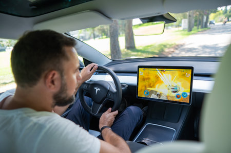 Novosibirsk, Russia - 10.08.2022: Caucasian man playing games while driving tesla car.