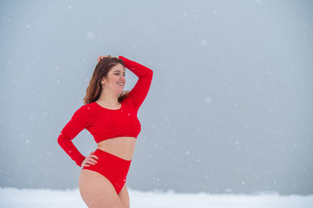 Caucasian red-haired woman posing in lingerie outdoors in winter.の写真素材