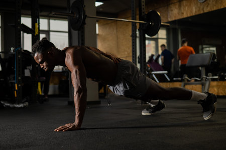 African american man doing one arm push ups in the gym.の写真素材