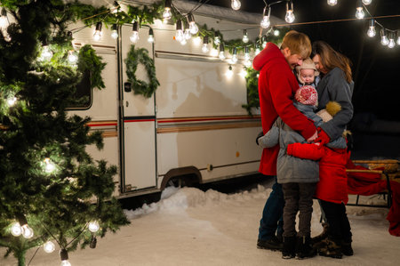 Happy caucasian family hugging outdoors. Christmas decorations. Parents and three sons travel in a camper.の写真素材