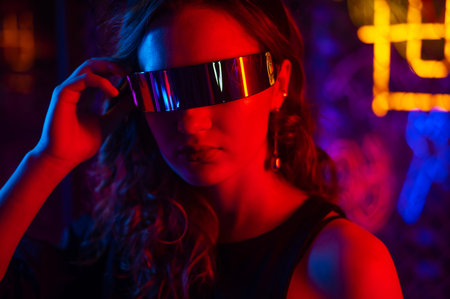 Caucasian woman in sunglasses posing in fog in neon studio.の写真素材