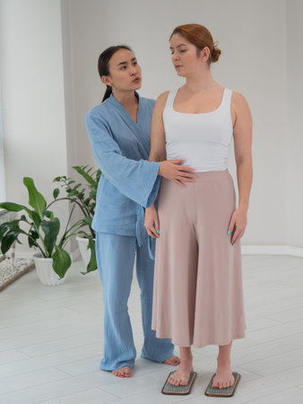 Caucasian woman stands on sadhu boards with therapist support.