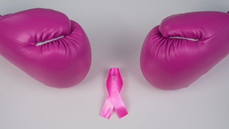 Pink boxing gloves and a pink silk ribbon on a white background. Breast cancer concept.の写真素材