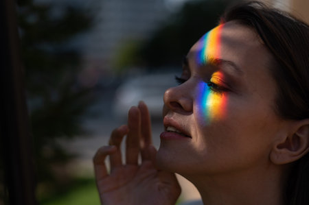 Portrait of caucasian woman with rainbow beam on her face outdoors.の写真素材