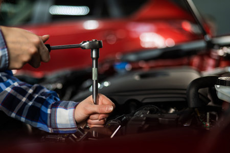 Female auto mechanic unscrewing a nut to replace a car spark plug.の写真素材